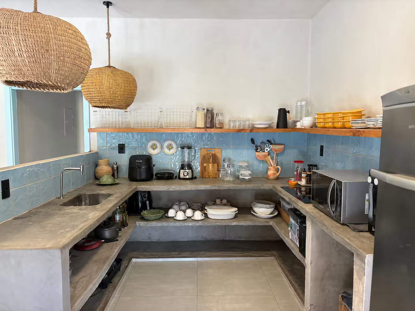 Cozinha equipada com bancada de cimento e azulejos azuis