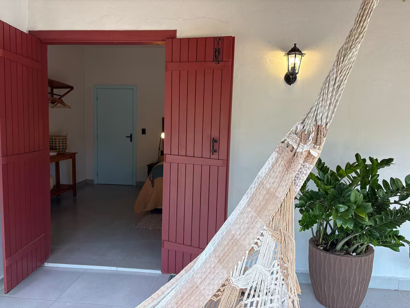 Entrada do quarto com rede na varanda e portas vermelhas